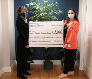 Two women stand on either side of a large check representing the donation eFS is making to the WRC. Both are wearing face masks.