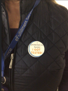 Photo is a close up of a eFS team members chest showing their eFS lanyard and a sticker that reads, "I protected my family! I got tested!"