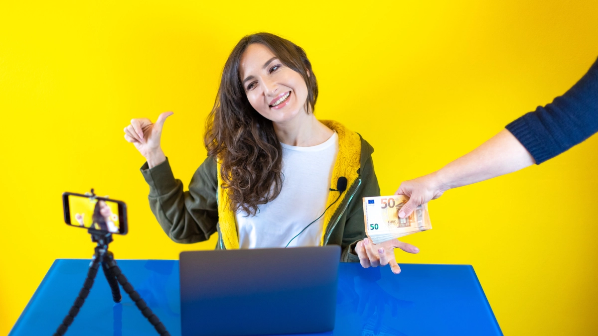 Female influencer in  green and yellow hoodie being paid for creating content in front of yellow background