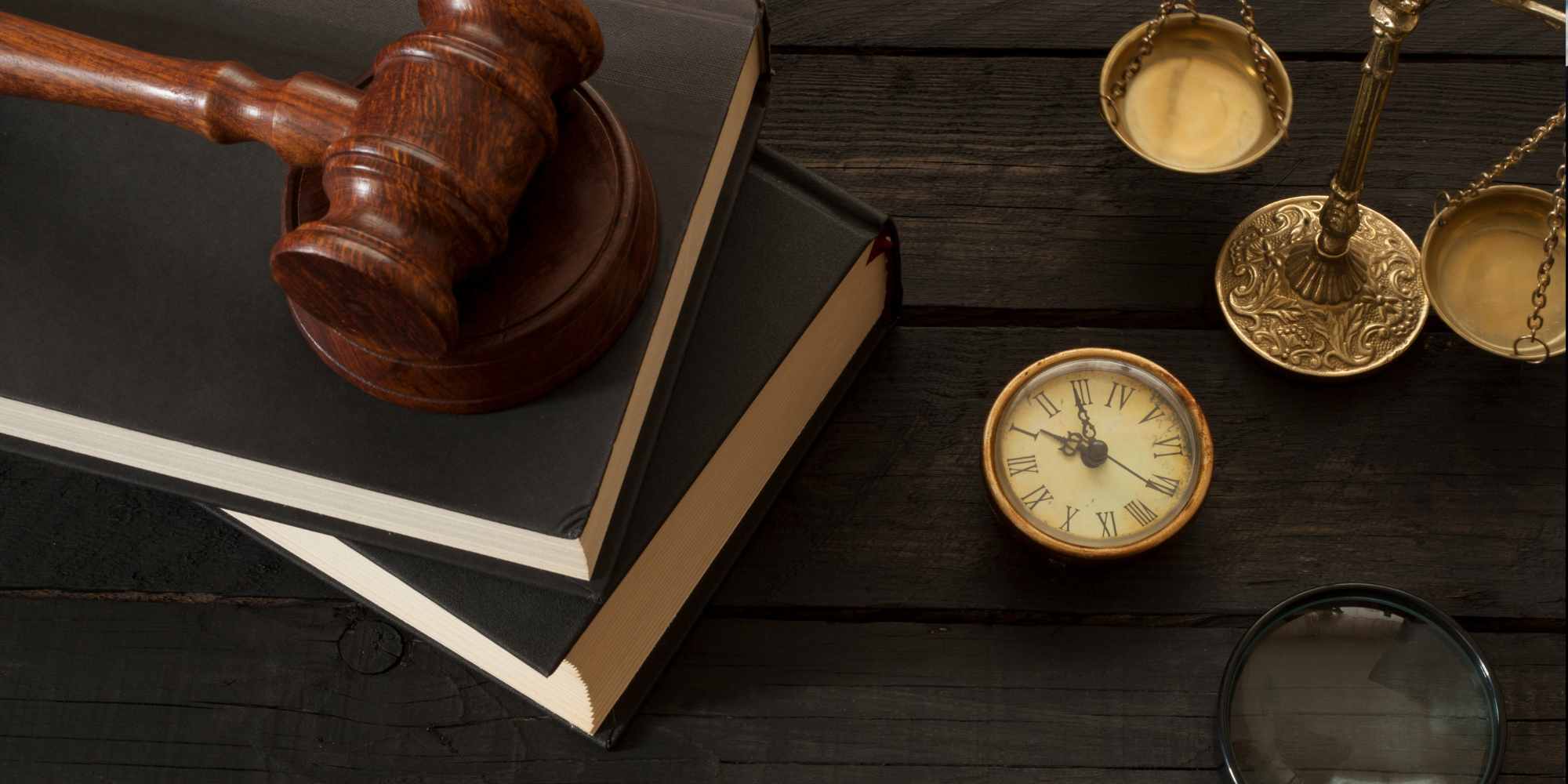 photo of a gavel on a stack of books next to golden scales