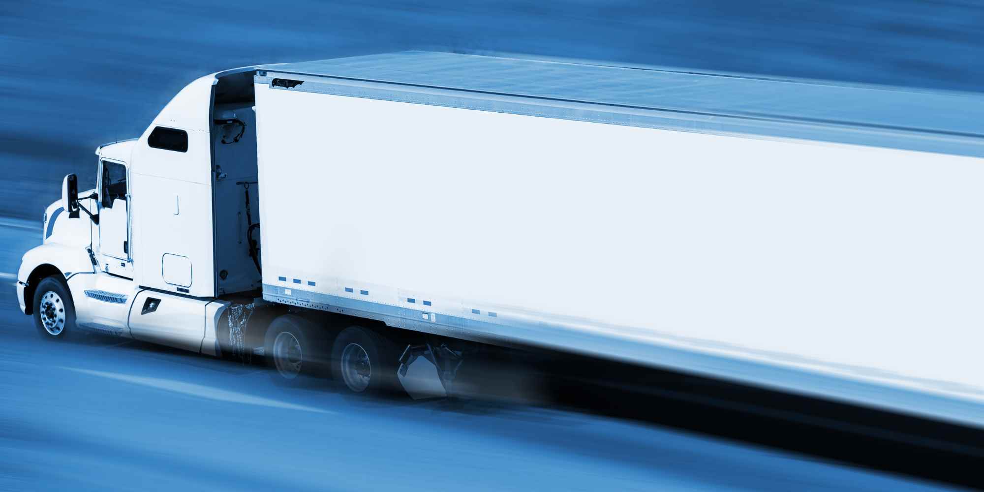 Photo of white semi delivery truck speeding down road